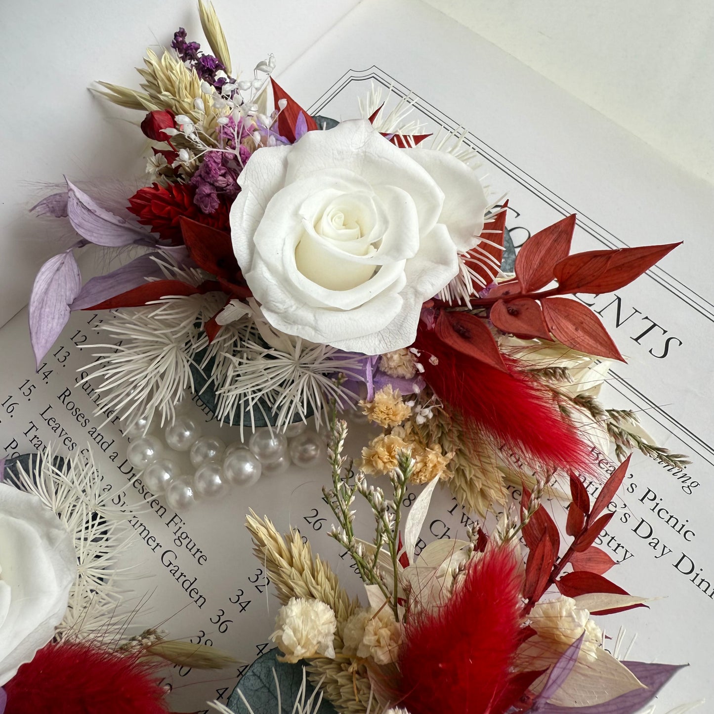 Decorative floral corsage with a white rose on top of a book