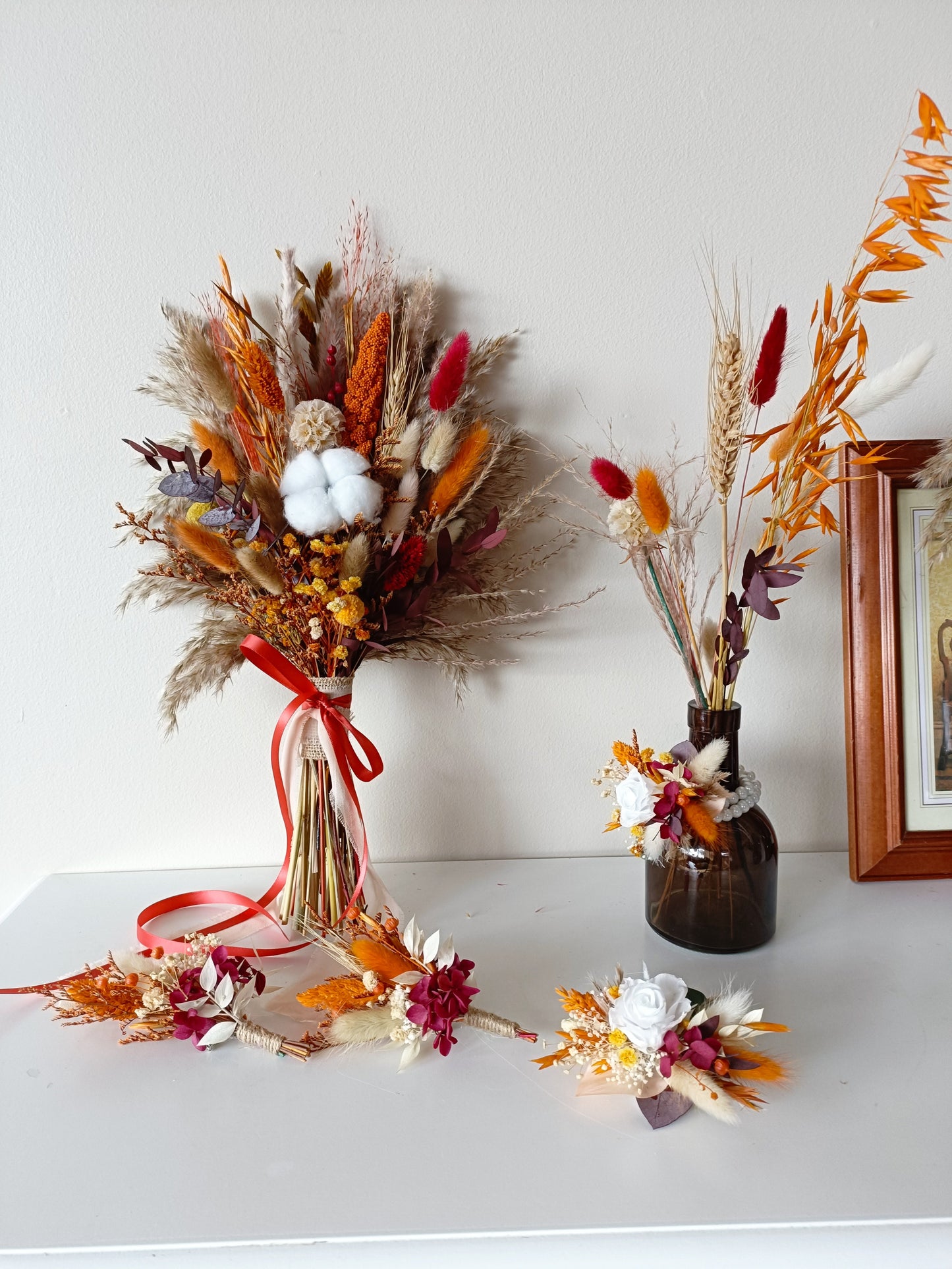 Rustic dried floral arrangement set including bridal bouquet and accessories in terracotta and cream tones.