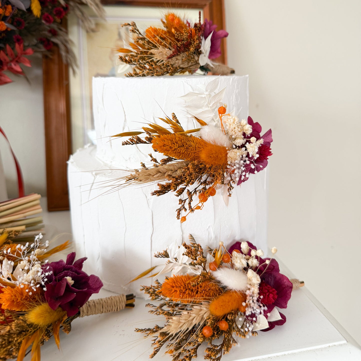 Boho style cake topper set made from dried flowers – pampas, cotton, terracotta, burgundy, rustic autumn wedding cake decoration. Decorative cake with autumnal flowers and wheat on a white surface.
