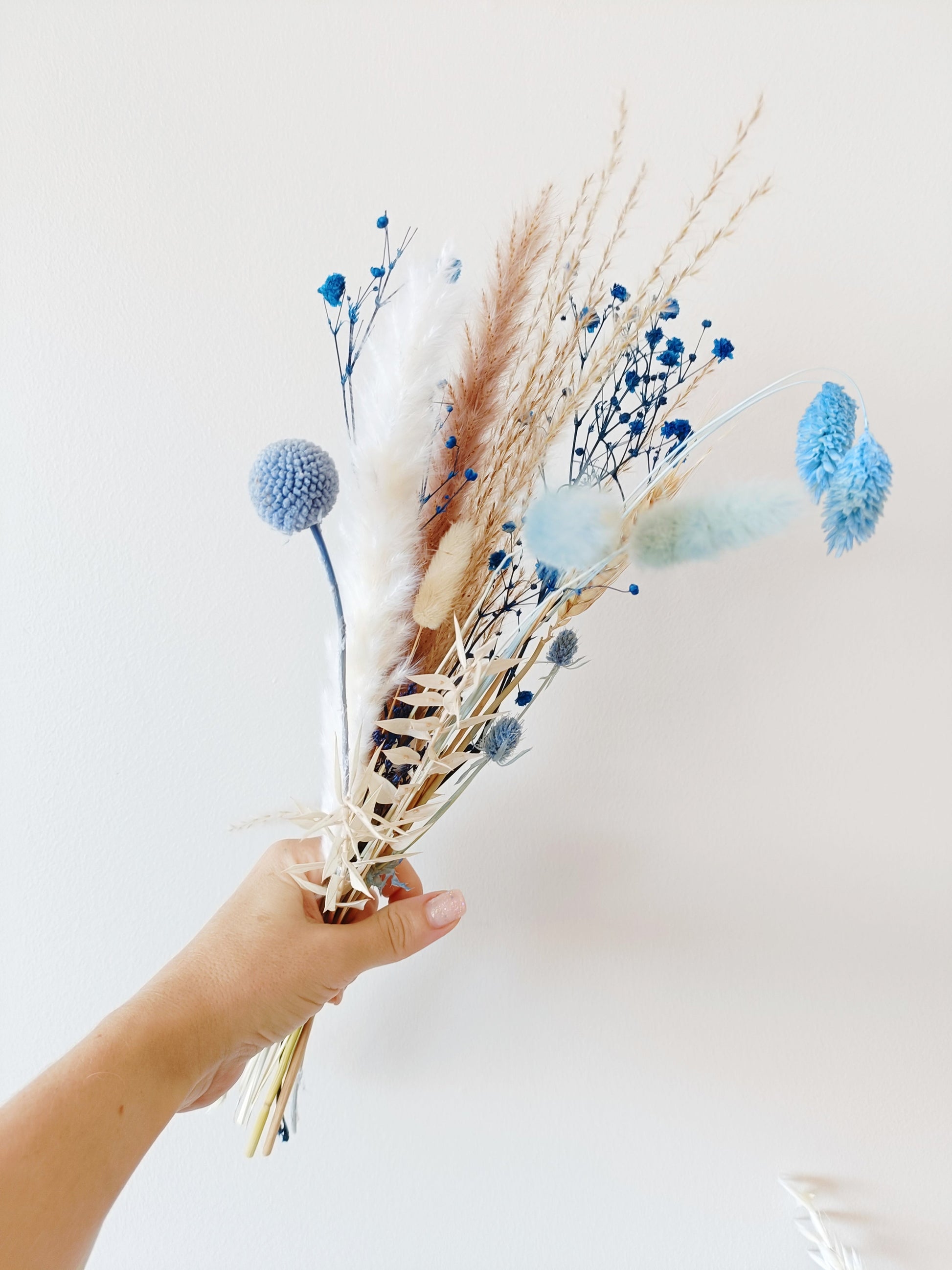 country-style flower decor, blue  flower setup, classic boho wedding flowers, vintage-inspired floral decor, delicate flower arrangement, stylish dried flower vase, timeless dried flowers, elegant table styling, wedding reception florals, beige flower display, soft aesthetic floral decor, dried palm leaf bouquet, artistic dried flowers, trendy boho arrangement, unique floral table setting, charming wedding centerpiece, aesthetic bohemian wedding, pampas grass styling, dreamy floral arrangement