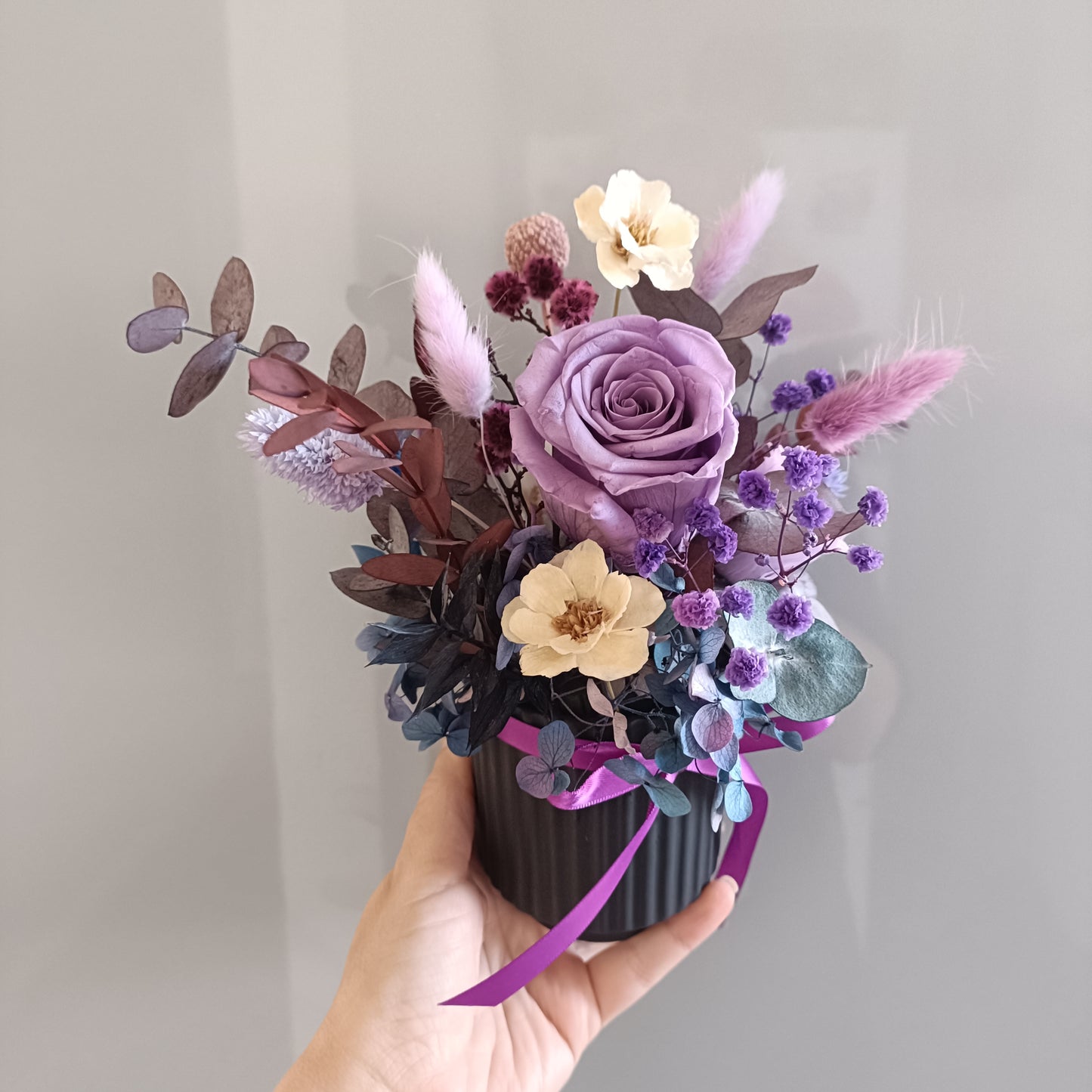 Hand holding a small dried floral arrangement