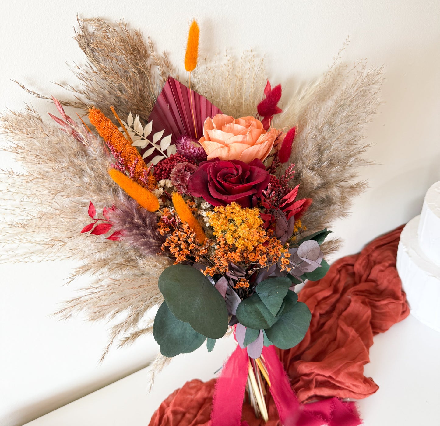 Terracotta and burgundy boho bridal bouquet with pampas, eucalyptus, and dried roses — a unique wedding bouquet made with natural dried flowers.