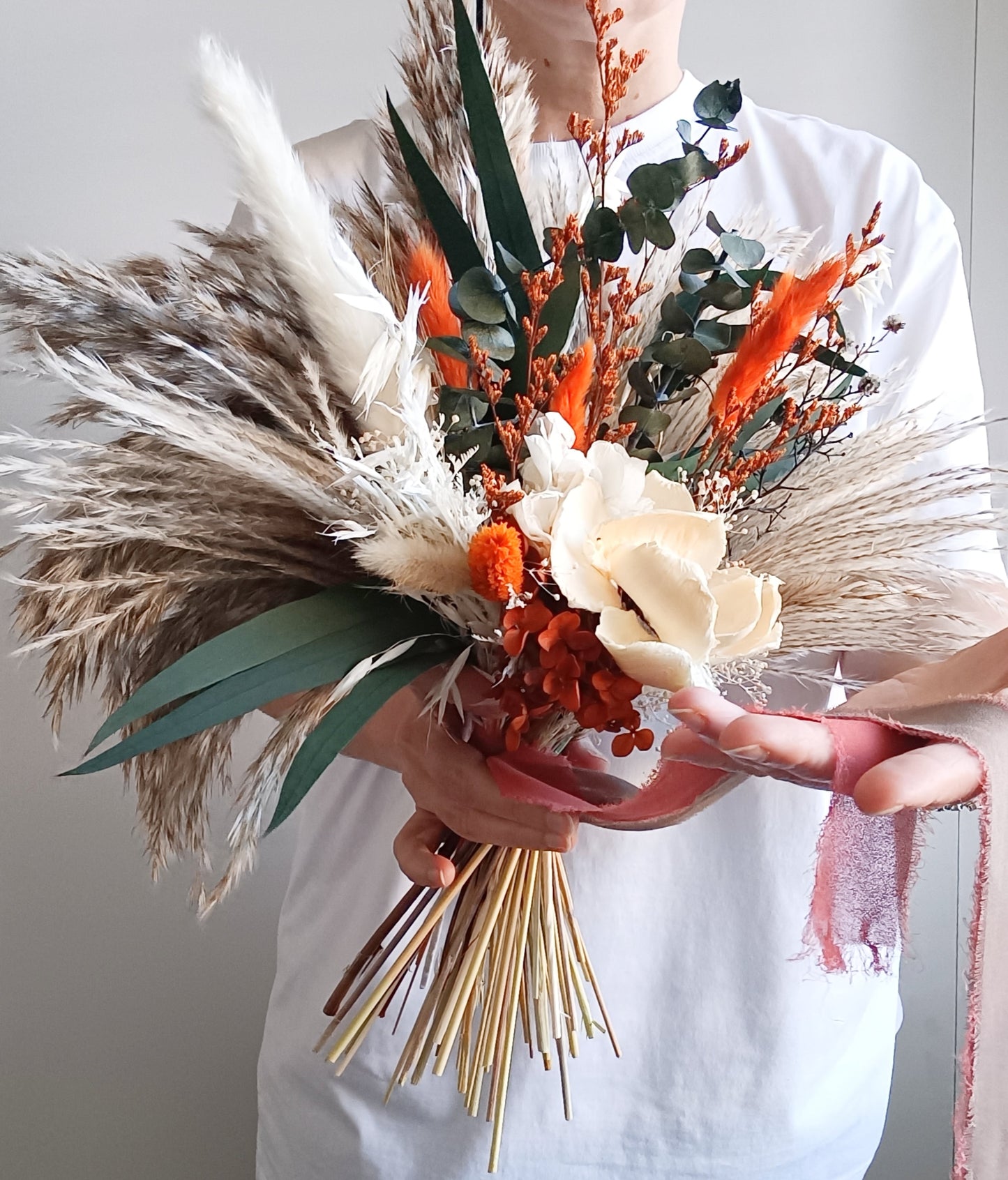Australian dried wedding bouquet in terracotta and ivory shades with preserved leaves, sola flowers, and pampas – perfect for boho brides