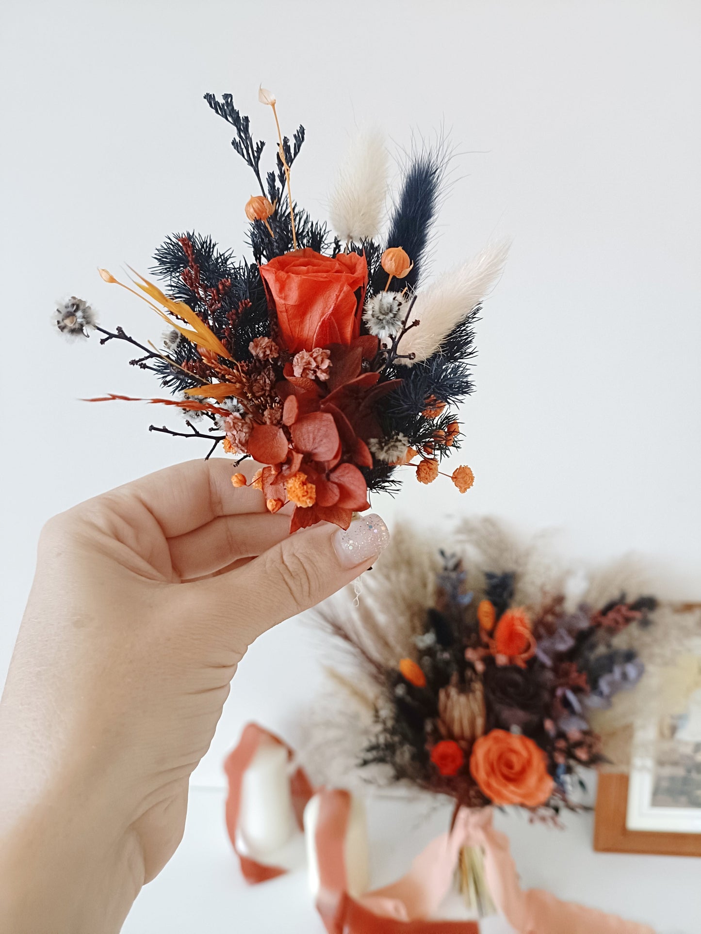 Dried flower boutonniere with preserved orange rose, bunny tails, and navy accents – handmade wedding accessory for groom or groomsmen.