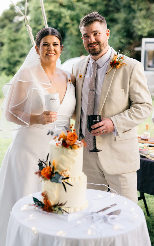 Handmade wedding cake floral decorations in terracotta rose tones, arranged with terracotta roses, warm orange blooms and dried foliage.