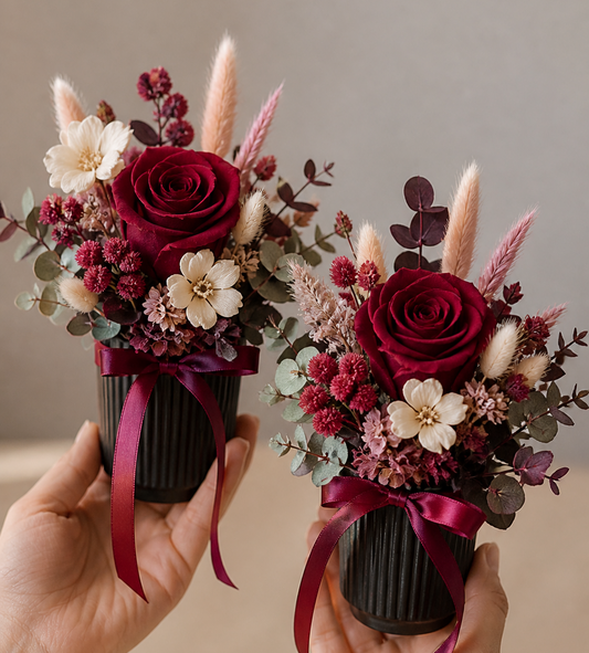  small floral arrangements with red and pink flowers held by hands against a neutral background