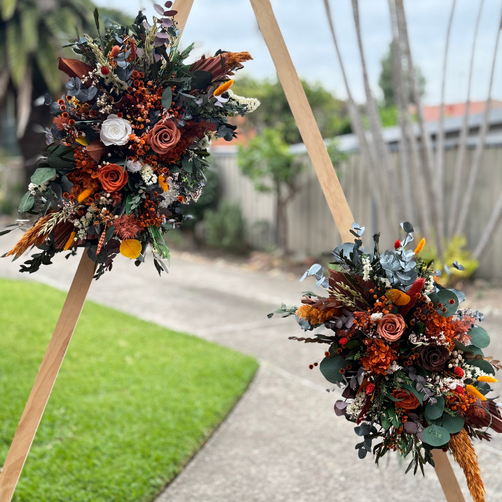 wedding floral arrangements on wooden stands with a blurred outdoor background