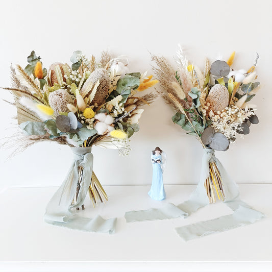 Neutral-toned wedding bouquet featuring dried banksia, yellow billy buttons, eucalyptus, and cotton – hand-tied and wrapped in a soft sage ribbon.