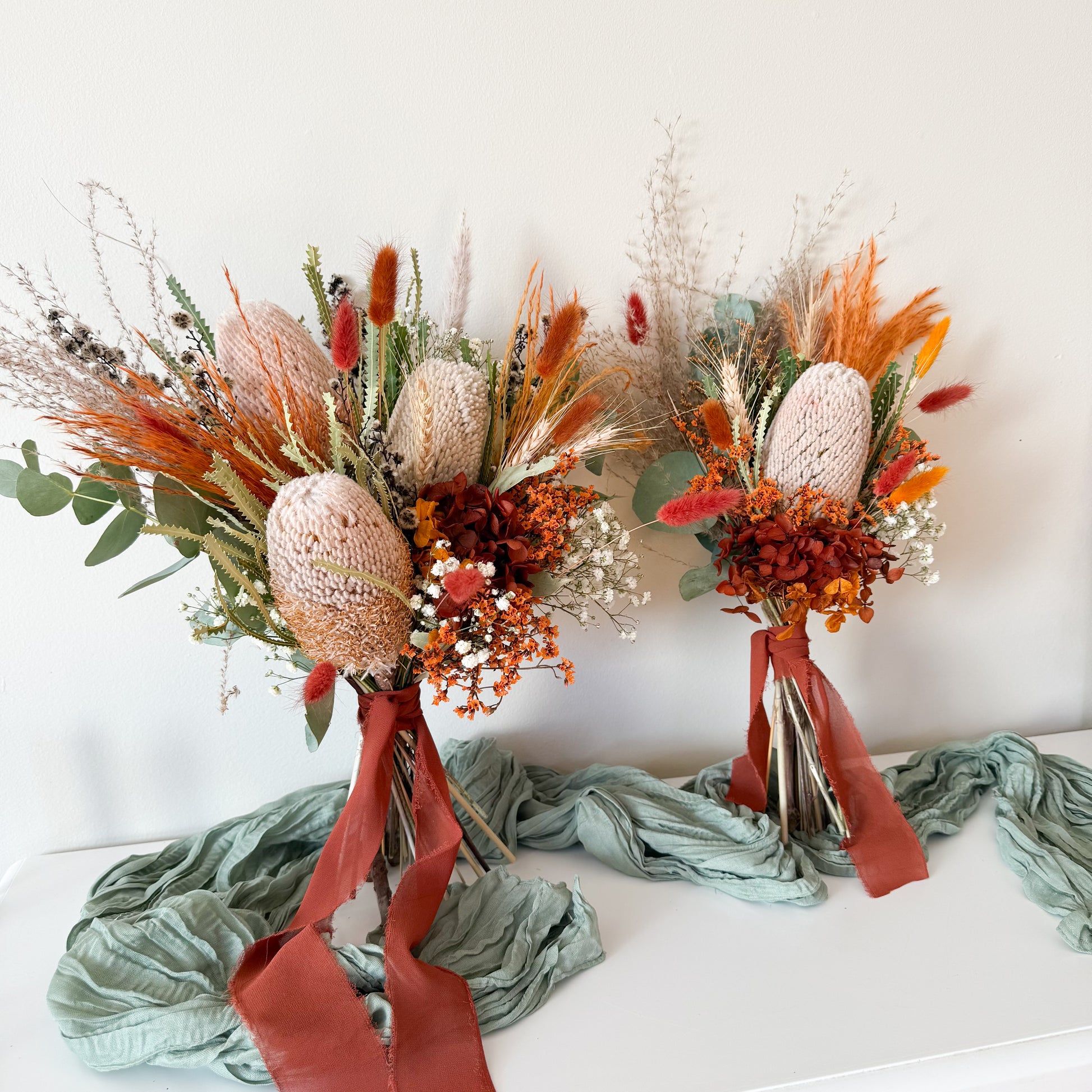 Dried floral arrangement duo with native Australian flowers and rich red and orange textures for rustic styling