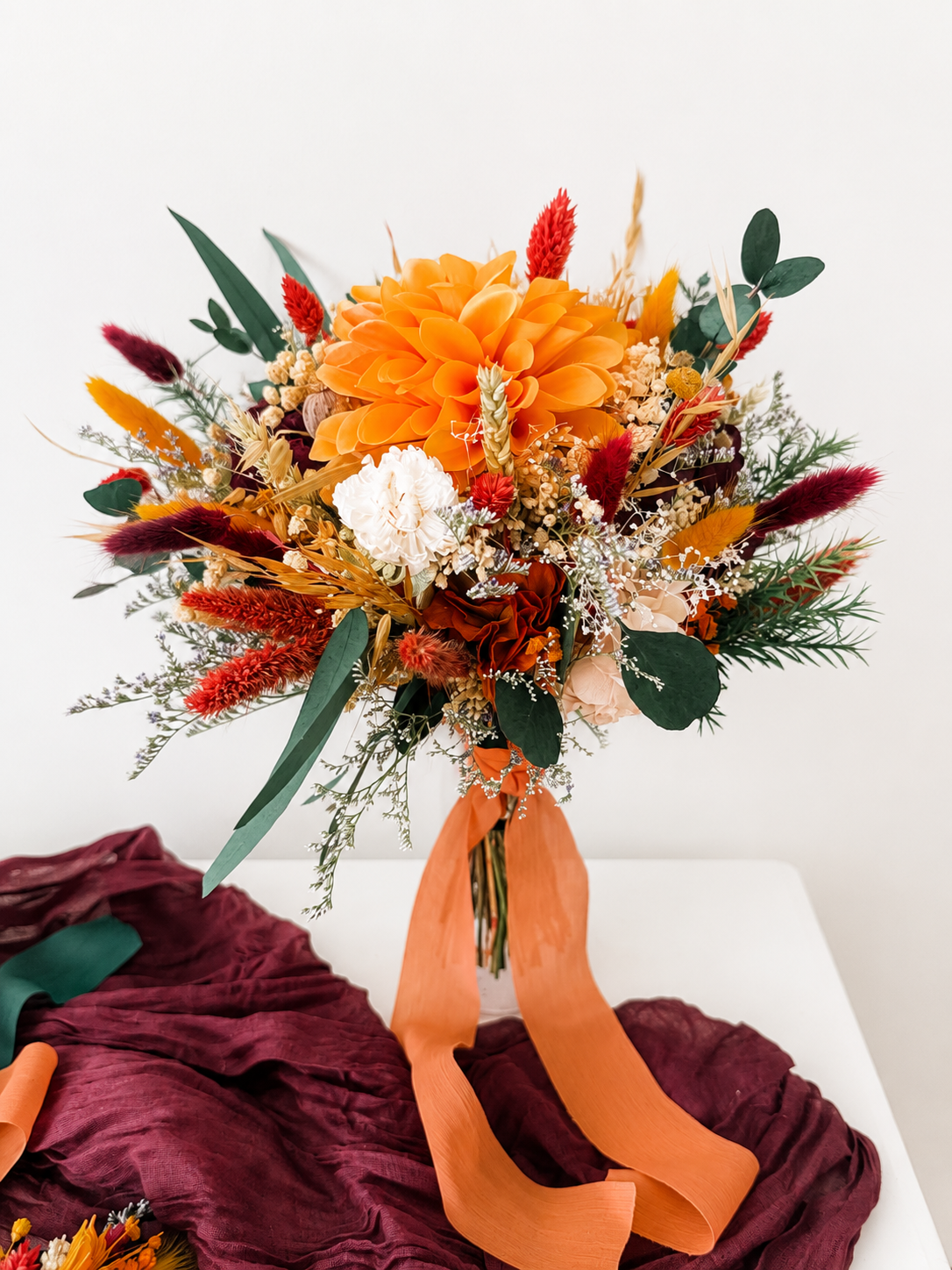 Handmade bridesmaid bouquet in burnt orange, burgundy and ivory preserved flowers with eucalyptus and dried grasses.