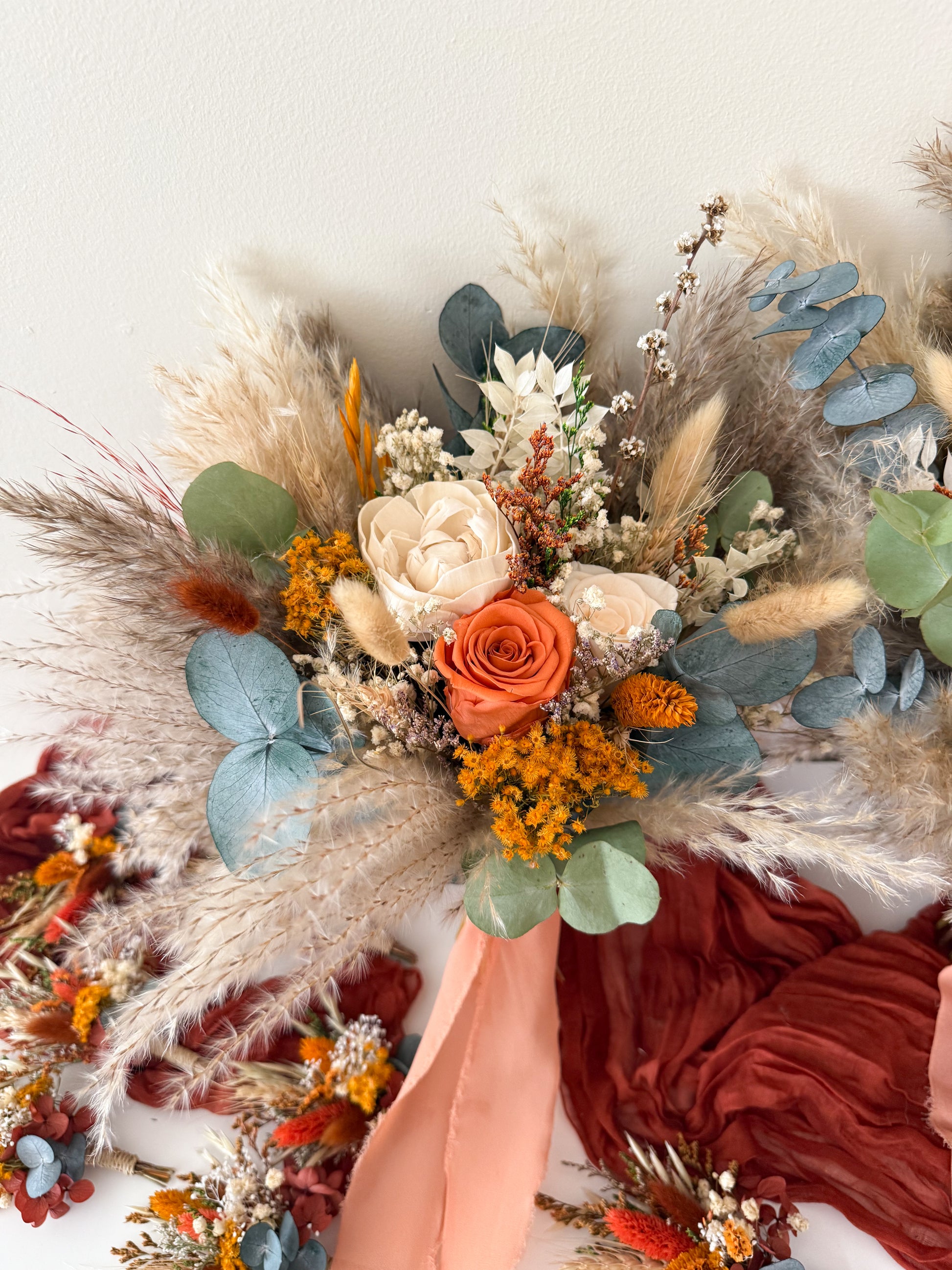 Bouquet of dried flowers and herbs held by a hand on a white background