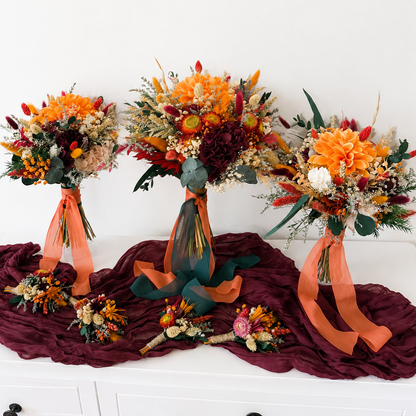 Complete autumn wedding flower set including bridal bouquet, bridesmaid bouquets and coordinating dried flower boutonnières in burnt orange and burgundy.