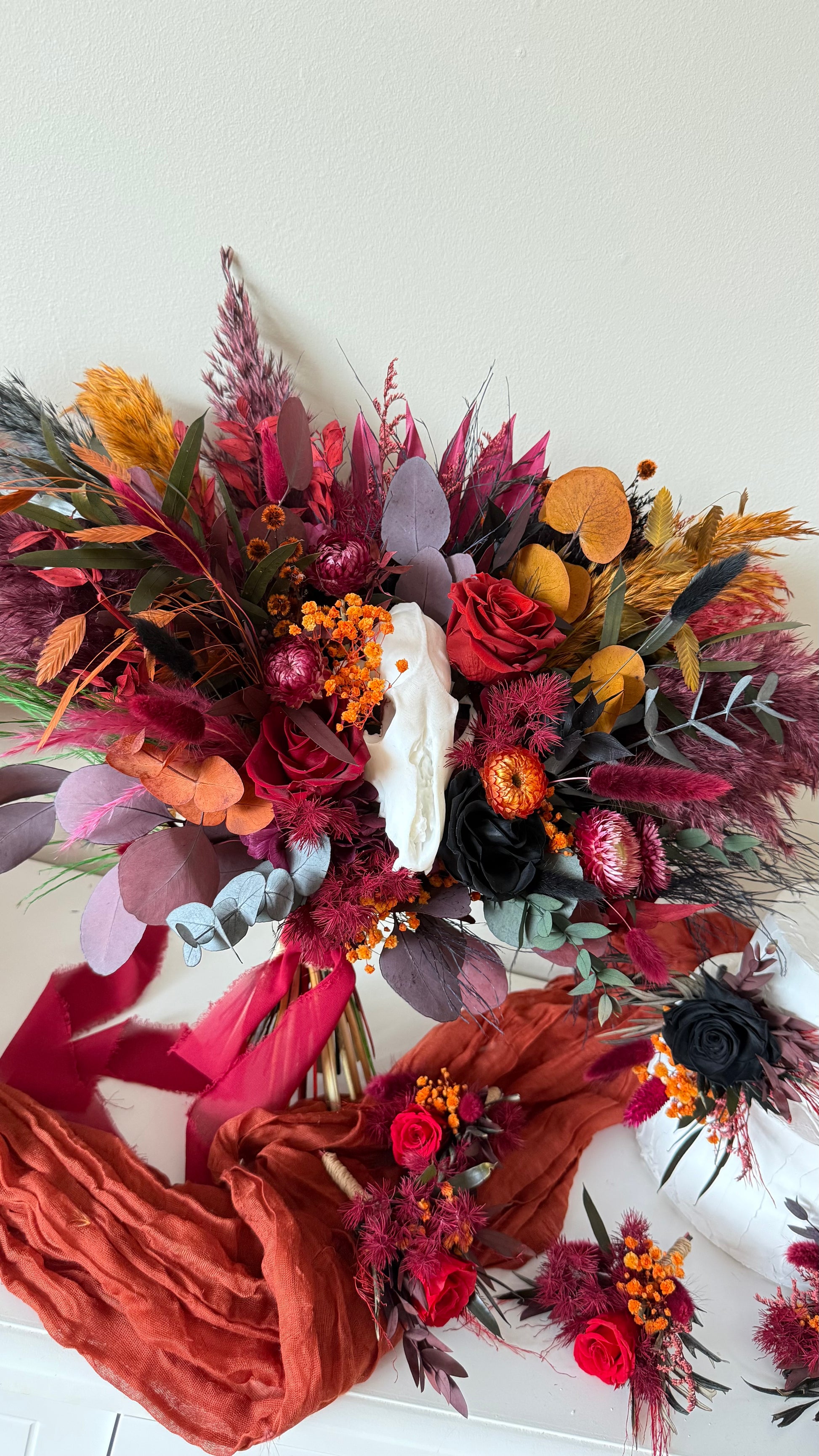 Bouquet of dried flowers with ribbons on a white background an white skull 