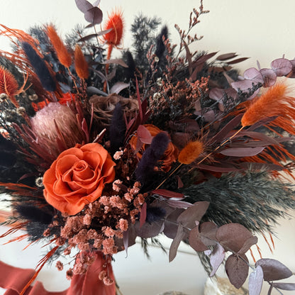 Bouquet of dried flowers with orange roses and various herbs on a neutral background