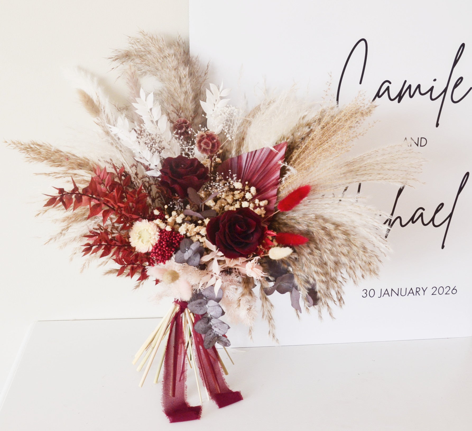 Large boho wedding bouquet with pampas grass, preserved burgundy roses and rustic dried flowers for bride.