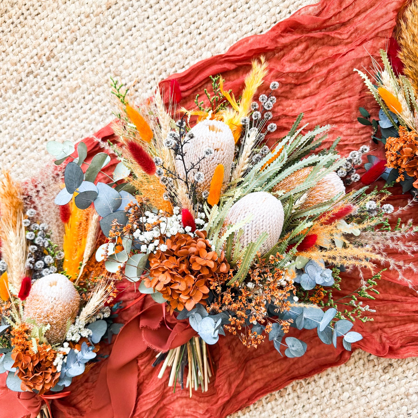 Boho wedding bouquet and matching arrangements featuring Australian native protea, pampas grass, and terracotta tones.