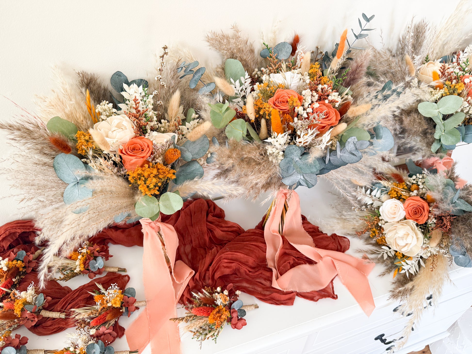 Rustic boho wedding bouquet featuring preserved orange and ivory roses, pampas grass, eucalyptus, and sola wood flowers, perfect for autumn Australian weddings.