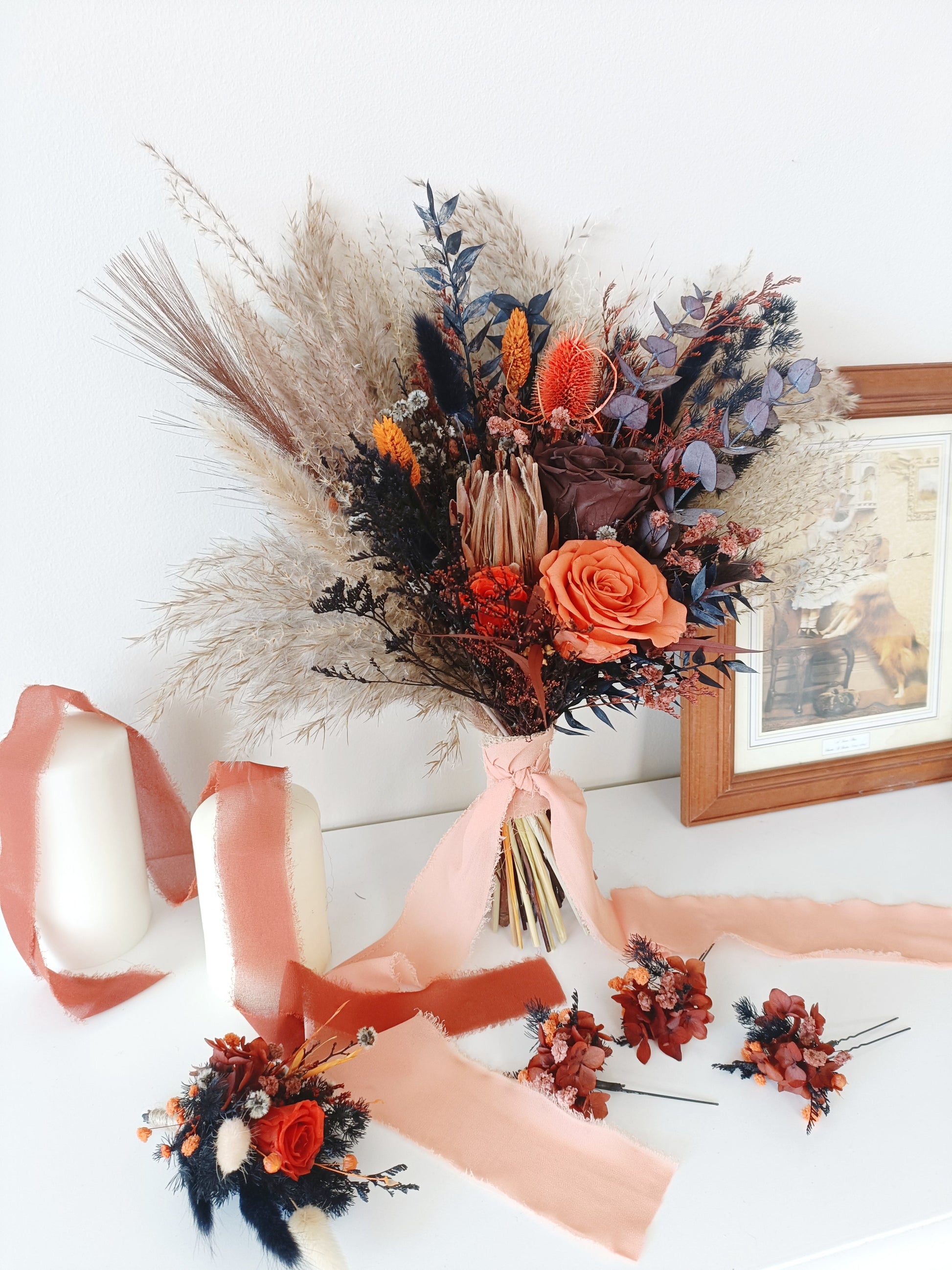 Bridal set of dried flowers in warm earthy tones – includes bouquet, boutonniere, and three matching hairpins, styled with peach ribbon and candles.