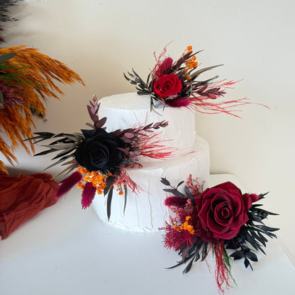 Burgundy and black preserved rose floral cake topper set on white tiered wedding cake