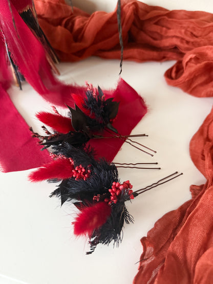 Red and black feathered hair accessories on a white background with red fabric.