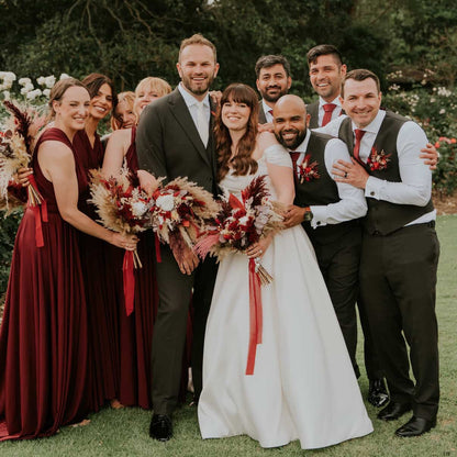 Bride and bridesmaids holding burgundy, red and ivory dried and preserved wedding flower bouquets with pampas grass at an outdoor wedding in Aust