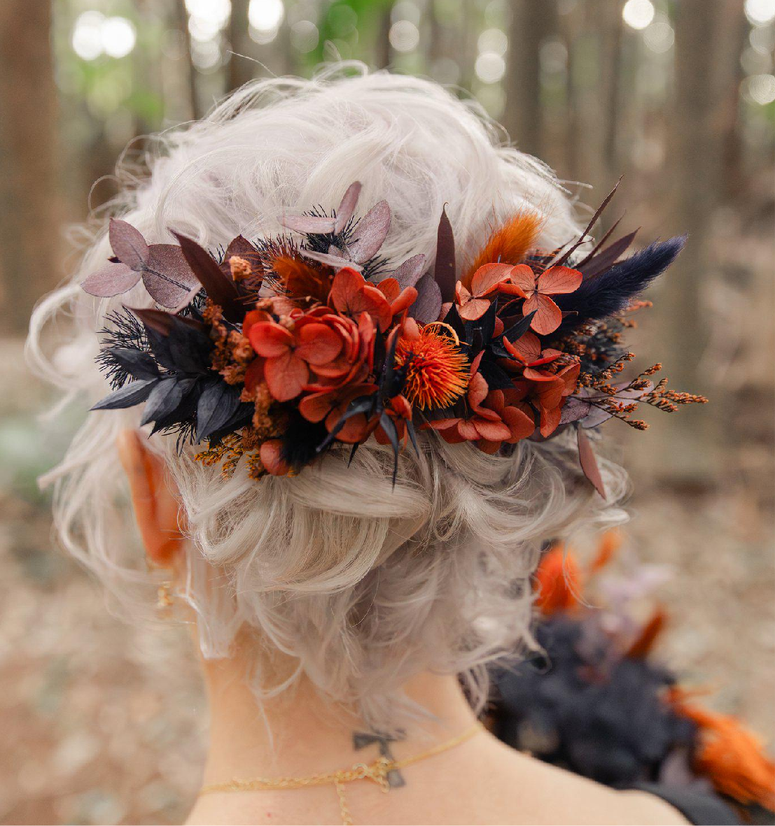 Bride wearing a burnt orange and black dried flower hairpiece with preserved hydrangea, Australian native blooms, and textured foliage, styled in an elegant updo for a boho wedding