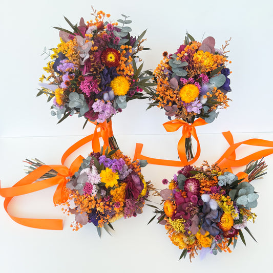 Colorful dried floral bouquets with orange ribbons on a white background