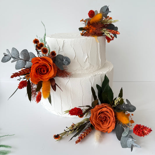 Dried flower cake toppers in burnt orange and ivory tones with preserved roses and eucalyptus for wedding cakes.