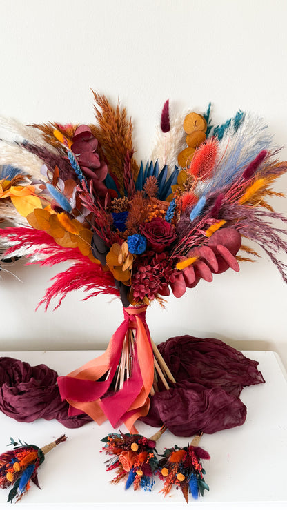 Colorful dried flower bouquet with red ribbon on a white surface
