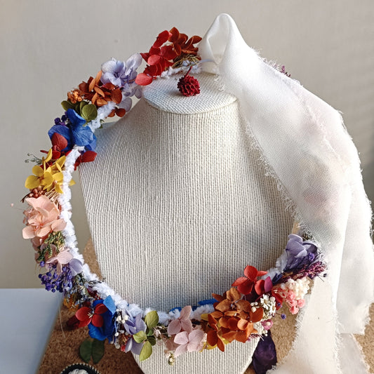 Colorful floral headpiece crafted from dried blooms, featuring orange, blue, pink, and yellow tones.