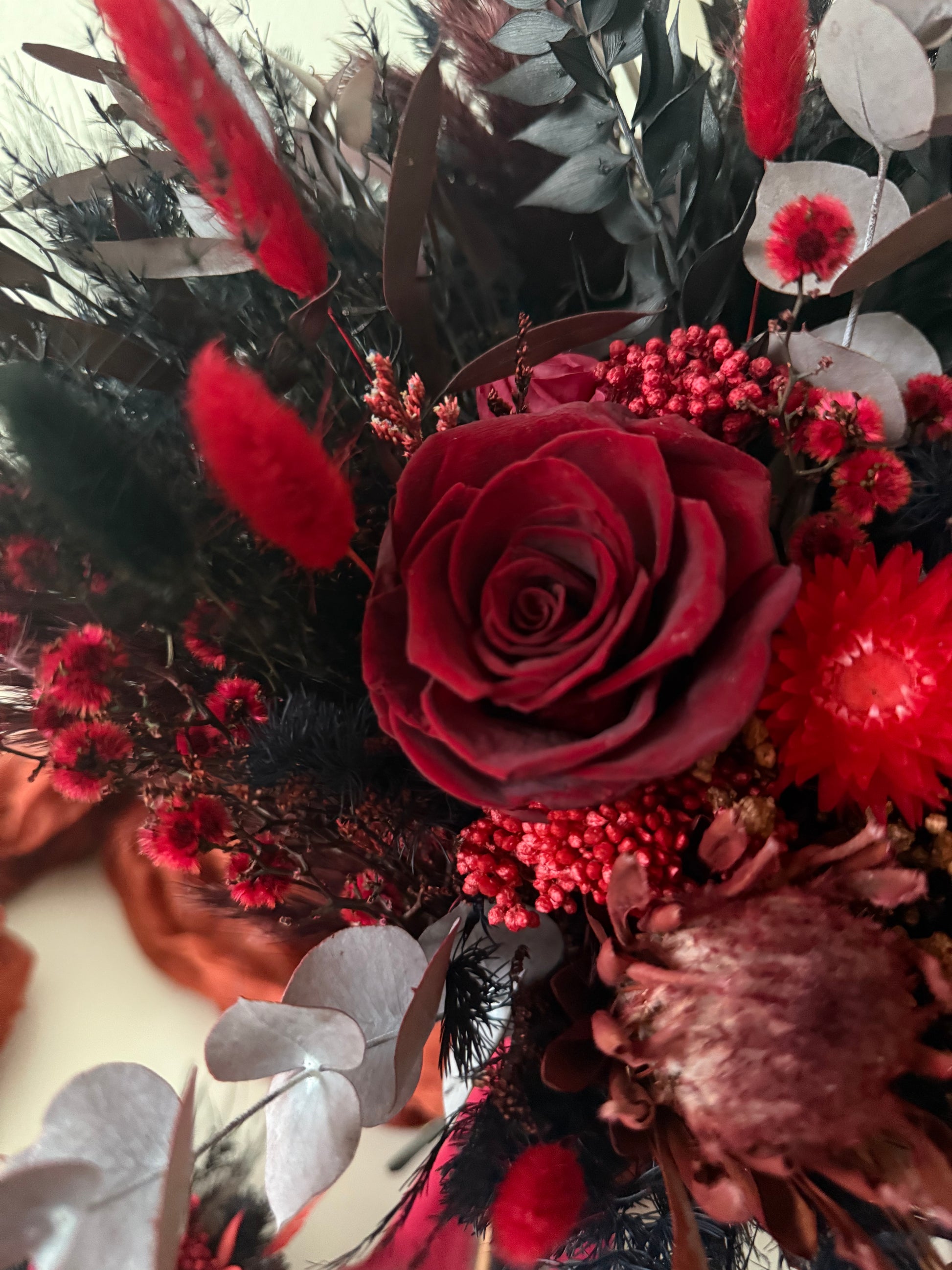 Dramatic alternative wedding bouquet in burgundy and black, dried flowers with preserved details.