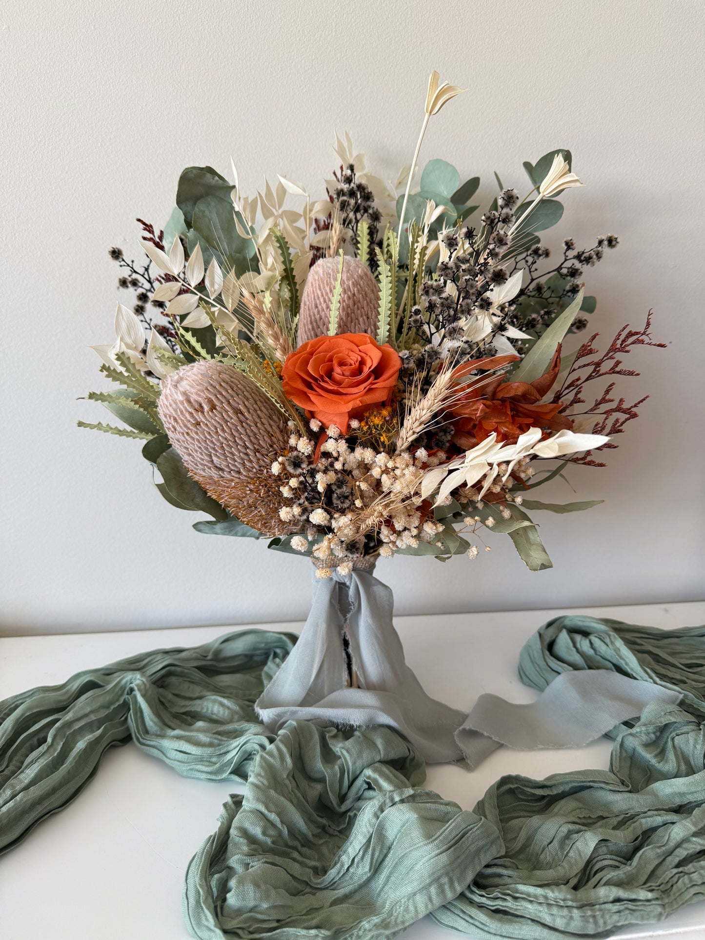 Rustic terracotta rose and banksia dried flower wedding bouquet with eucalyptus, boho natural Australian native style.