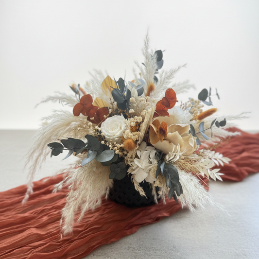 Decorative floral arrangement with dried elements on a textured surface