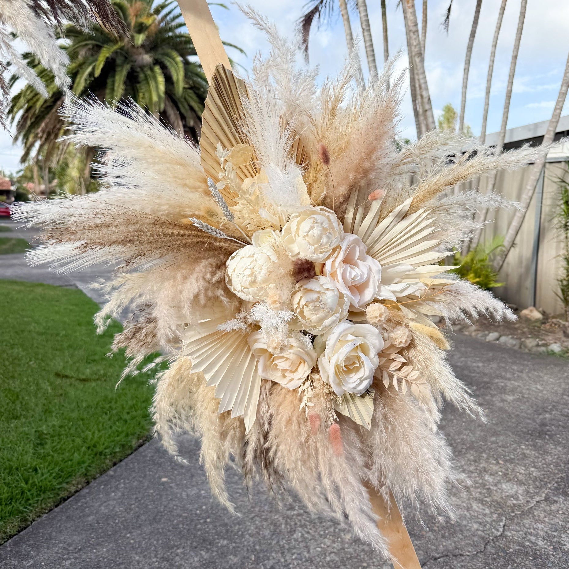 Wedding ceremony backdrop with pampas grass and sola peonies, styled in neutral tones for elegant outdoor celebrations.