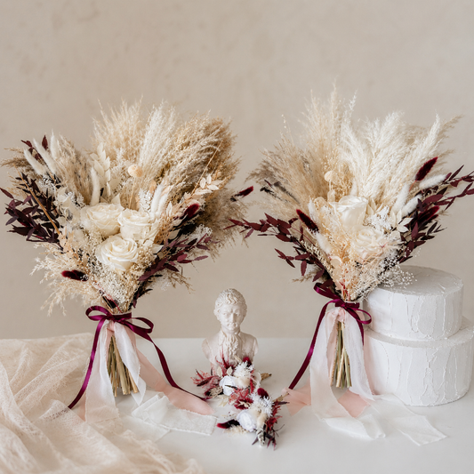 Two dried flower bouquets with ribbons on a neutral background