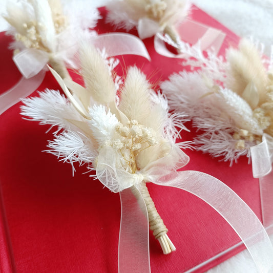 Dried flower boutonniere in ivory tones with lagurus and baby's breath tied with sheer ribbon
