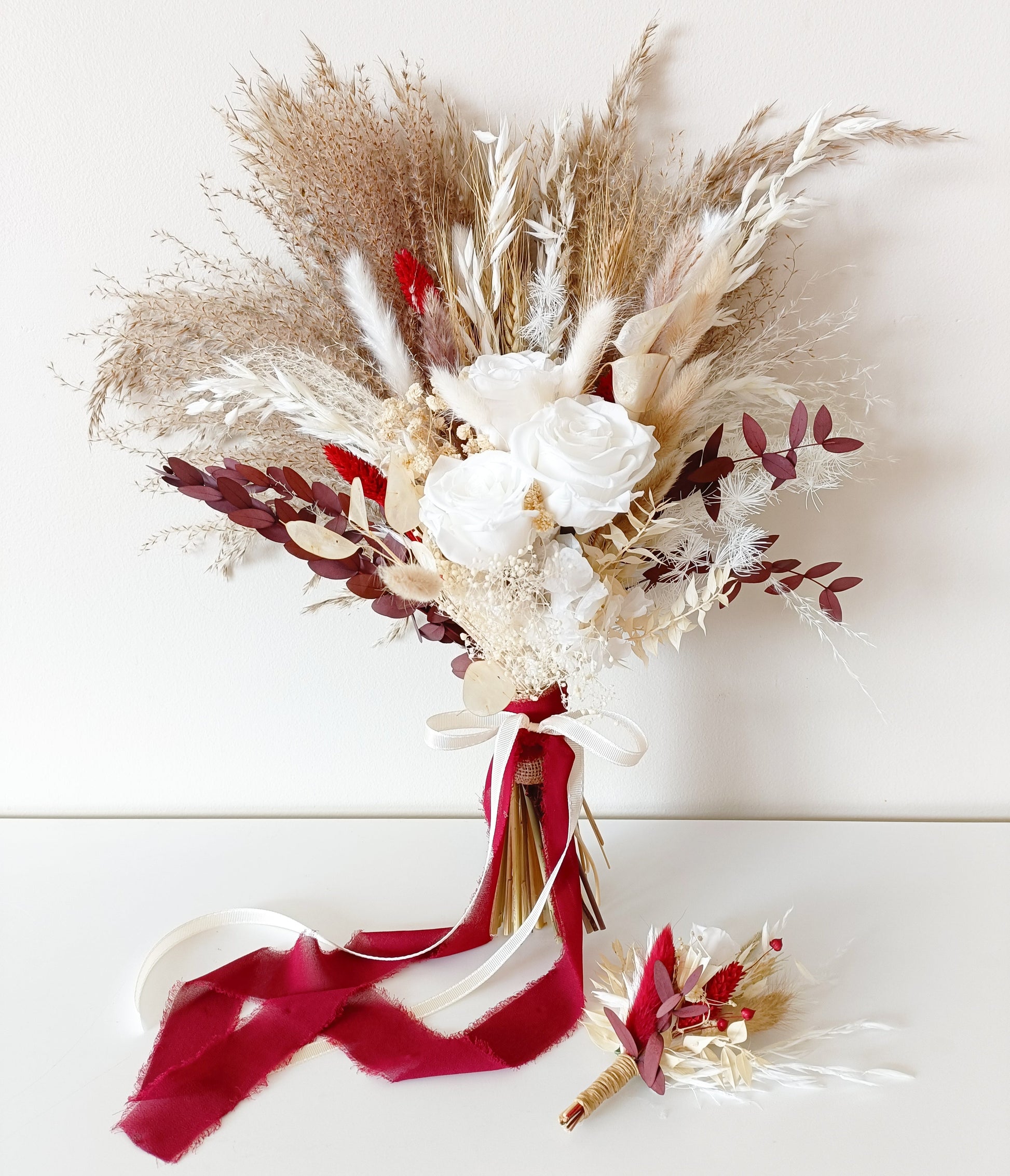 Dried flower bridal bouquet in ivory, beige and burgundy tones with pampas grass, sola roses, preserved leaves and bunny tails, finished with a deep red velvet ribbon. Includes matching boutonnière. Perfect for rustic, boho or autumn weddings in Australia.