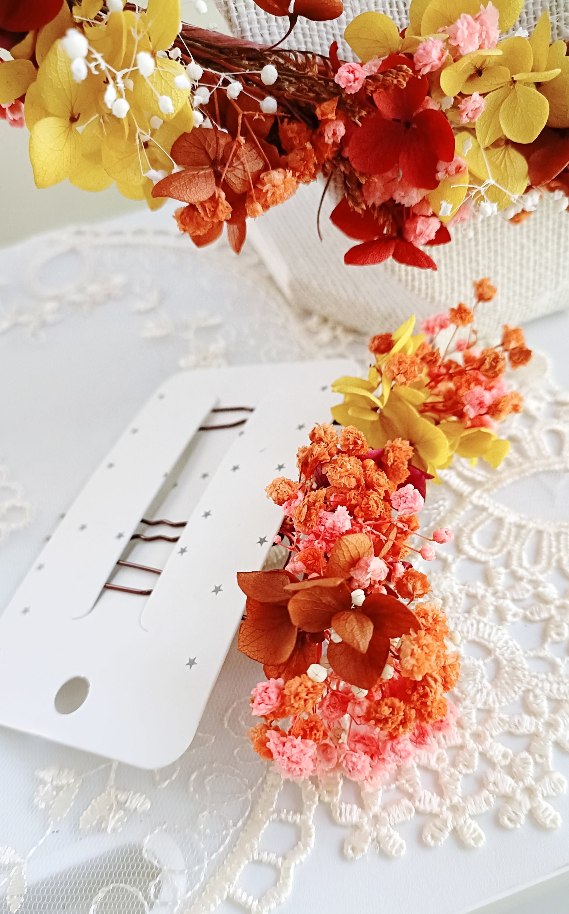  set of two handcrafted hair clips made from preserved colourful flowers. The clips are detailed with delicate pearl clusters and accented with natural textures for a bohemian feel.