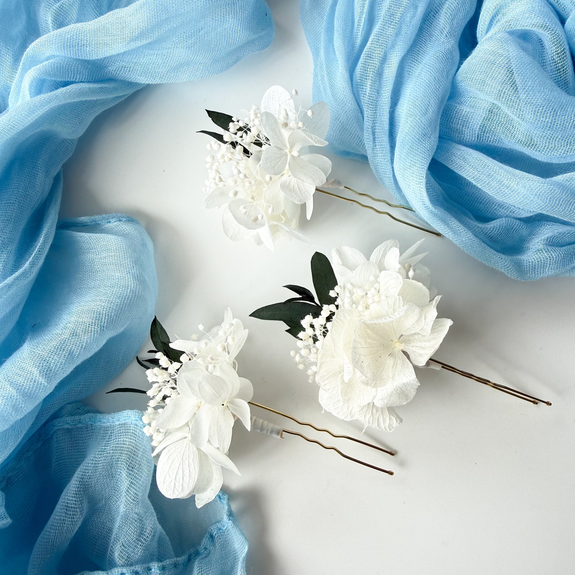 White floral hairpins on a light blue fabric background
