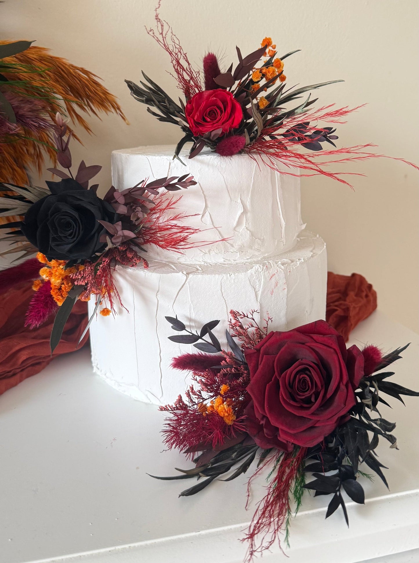 Moody wedding cake decorated with dried flowers and deep red preserved roses