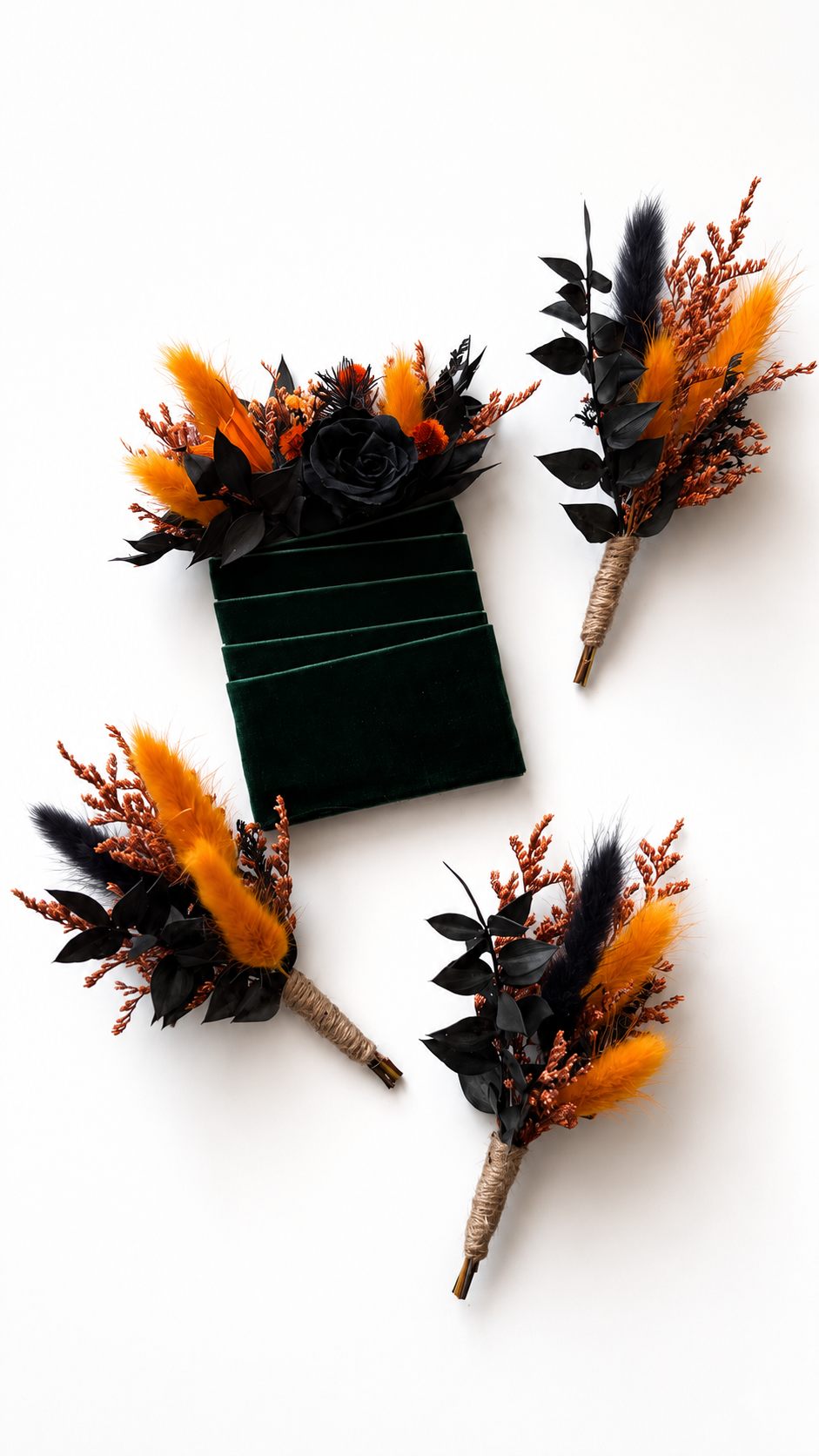 Three dried floral boutonnieres with black and orange botanicals are arranged around a dark green velvet box on a clean white background.