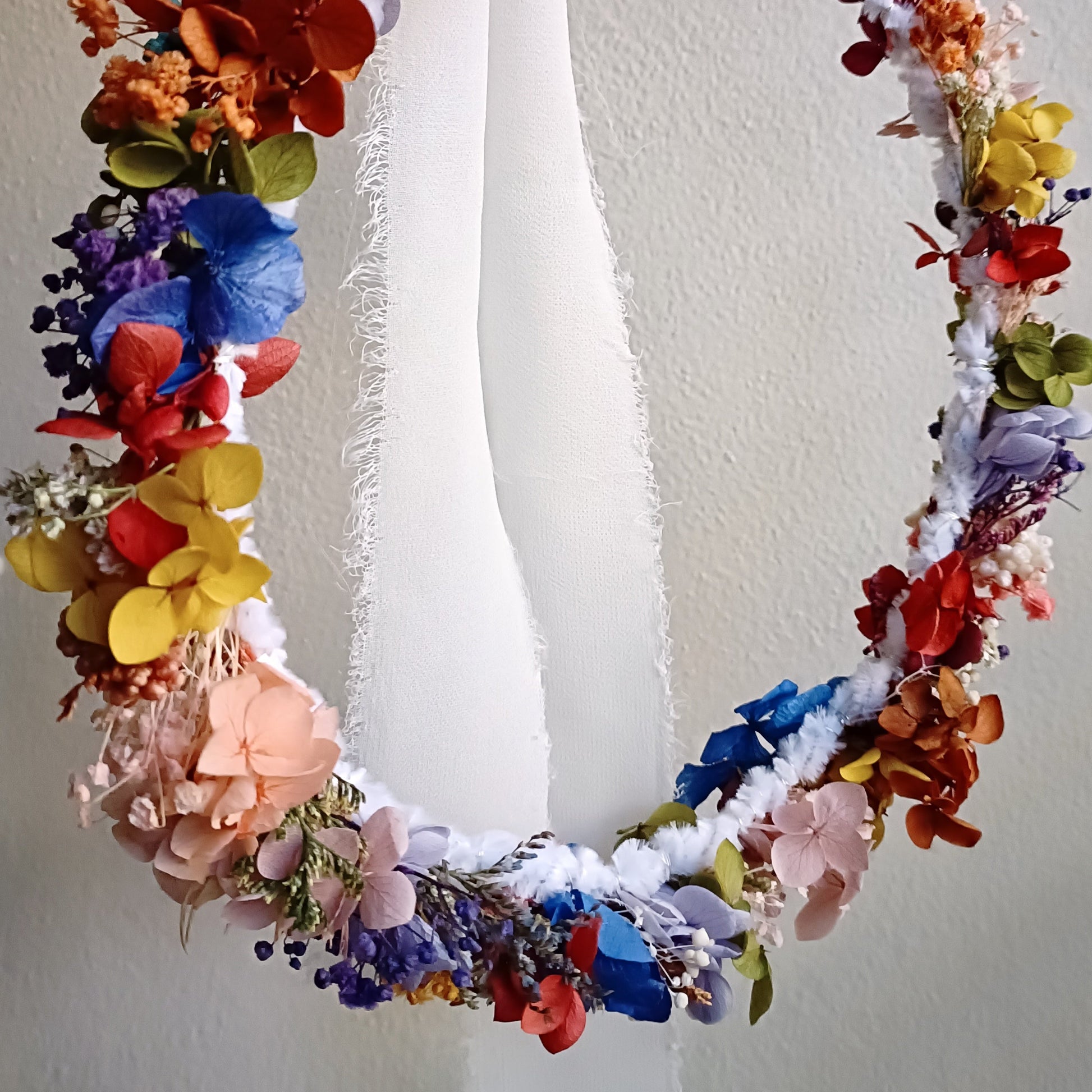 Handmade dried flower crown in vibrant boho colors with white ribbon ties.