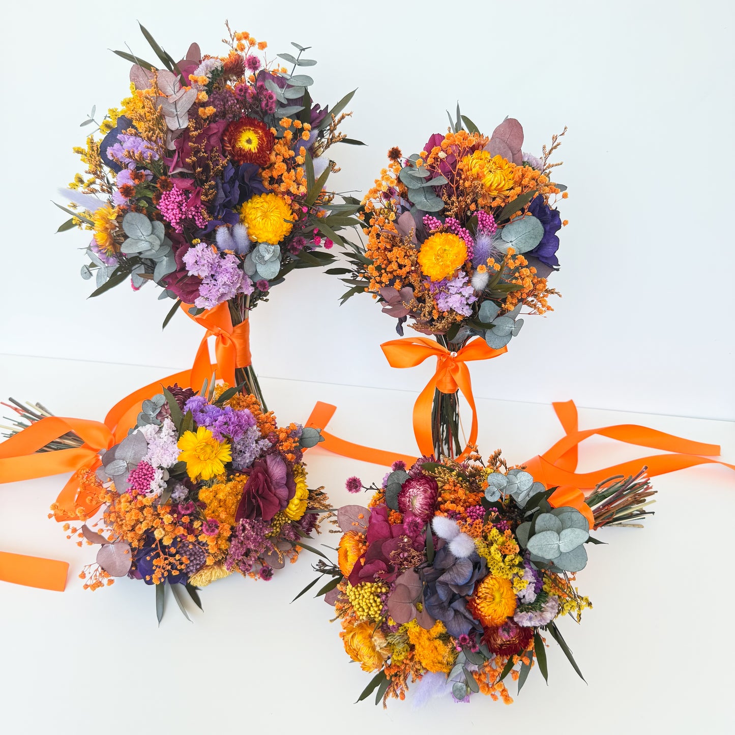 Four colorful flower bouquets with orange ribbons on a white background