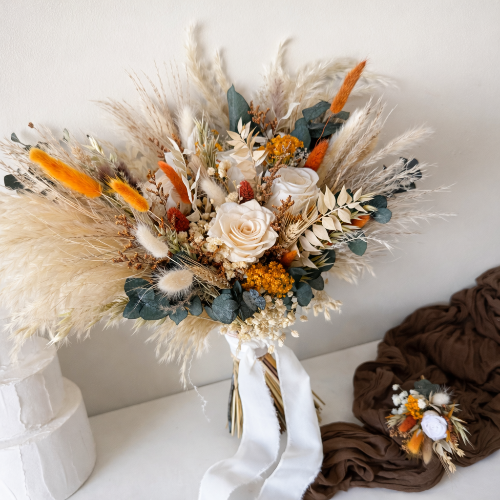 Dried ivory wedding bouquet with white roses, pampas grass and burnt orange accents for boho weddings