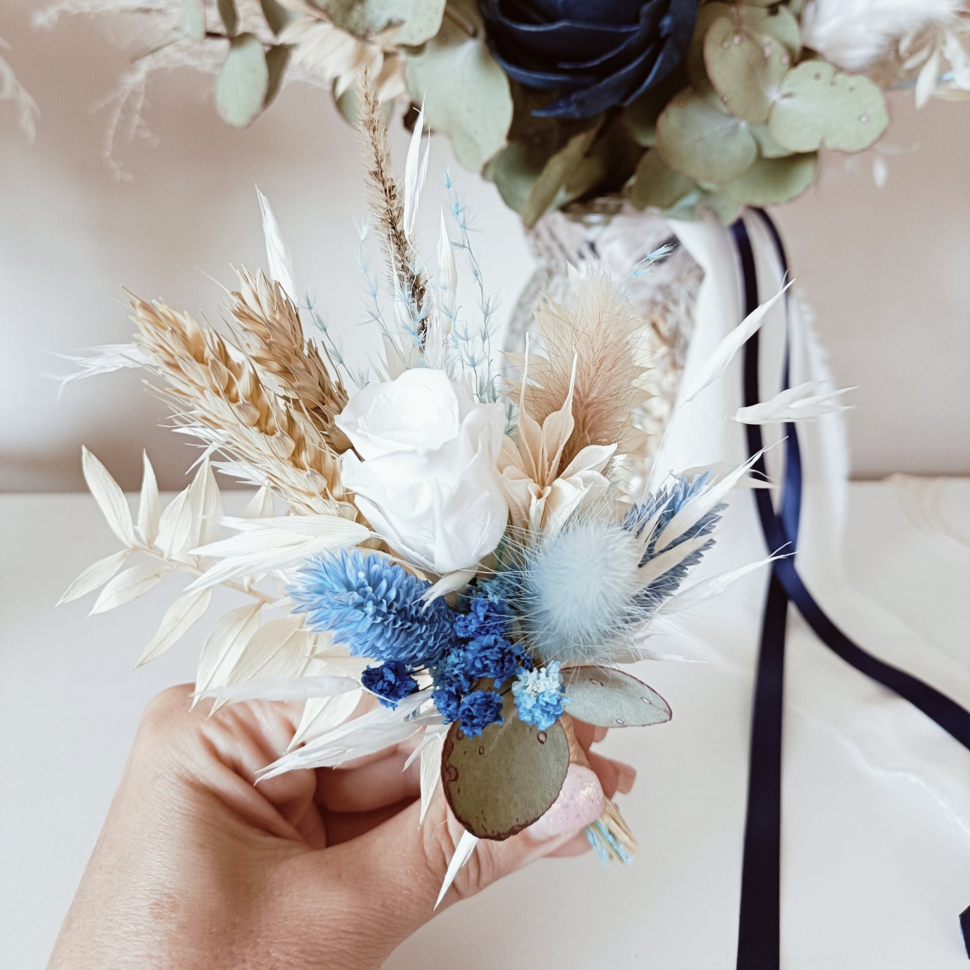 Navy and ivory dried flower boutonniere with sola rose, bunny tail, and preserved foliage – perfect match for groom or groomsmen.