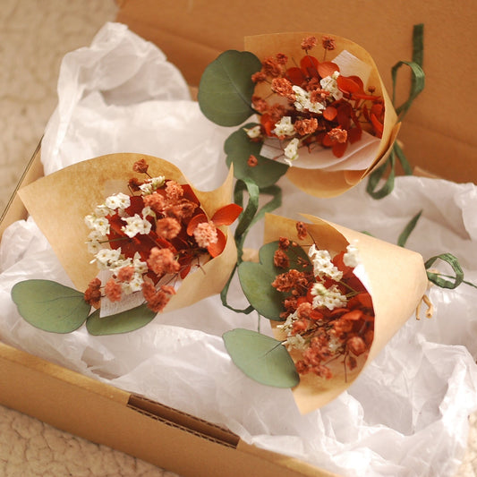 Mini bouquet in earthy terracotta and ivory tones, placed inside a kraft gift box lined with white tissue. Dried flowers include babyâ€™s breath, strawflowers, and eucalyptus. Ideal for wedding favours or small gifts. Presented in elegant eco-friendly packaging, perfect for rustic or boho-themed occasions.

