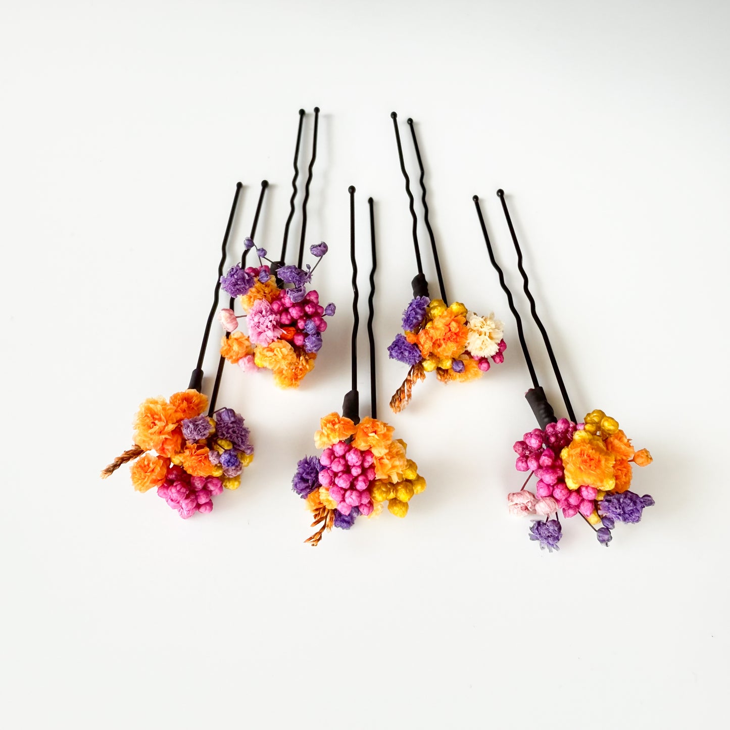 Colorful floral hairpins on black bobby pins against a white background