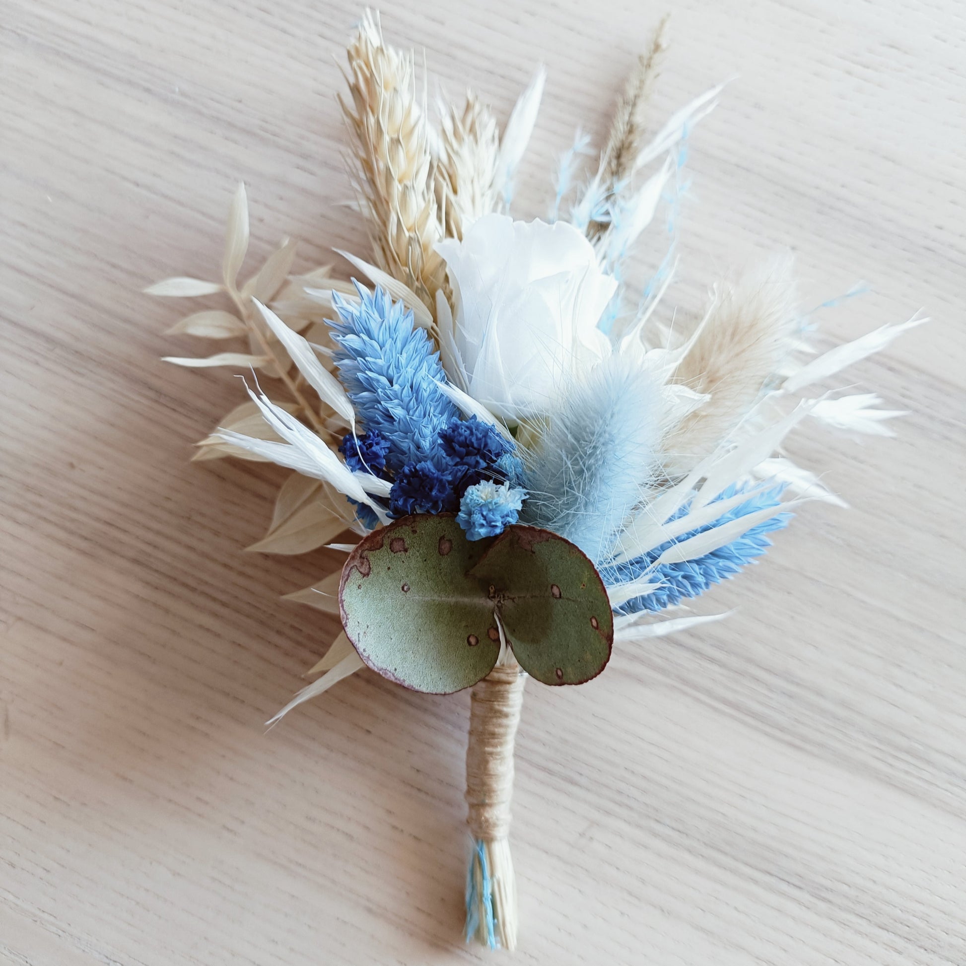 Navy and ivory dried flower boutonniere with sola rose, bunny tail, and preserved foliage – perfect match for groom or groomsmen.