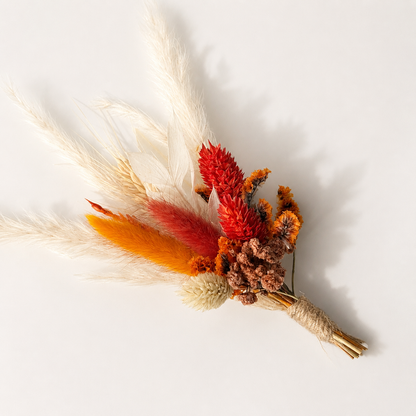 Handmade mini dried flower bouquet featuring orange, red and neutral preserved flowers with rustic wedding style.