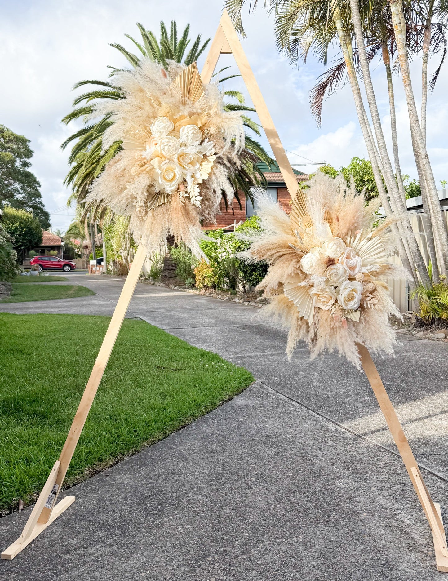 Outdoor wedding ceremony decor with pampas grass and sola peony floral arrangements, styled for modern neutral weddings.